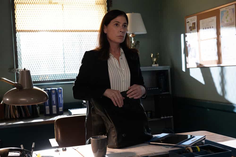 Law & Order Season 25 Episode 7 “Guardian” – Photos & Case Preview 2 Maura Tierney as Lieutenant Jessica Brady stands in the precinct office reviewing her bag during the Guardian case in Law & Order Season 25 Episode 7.