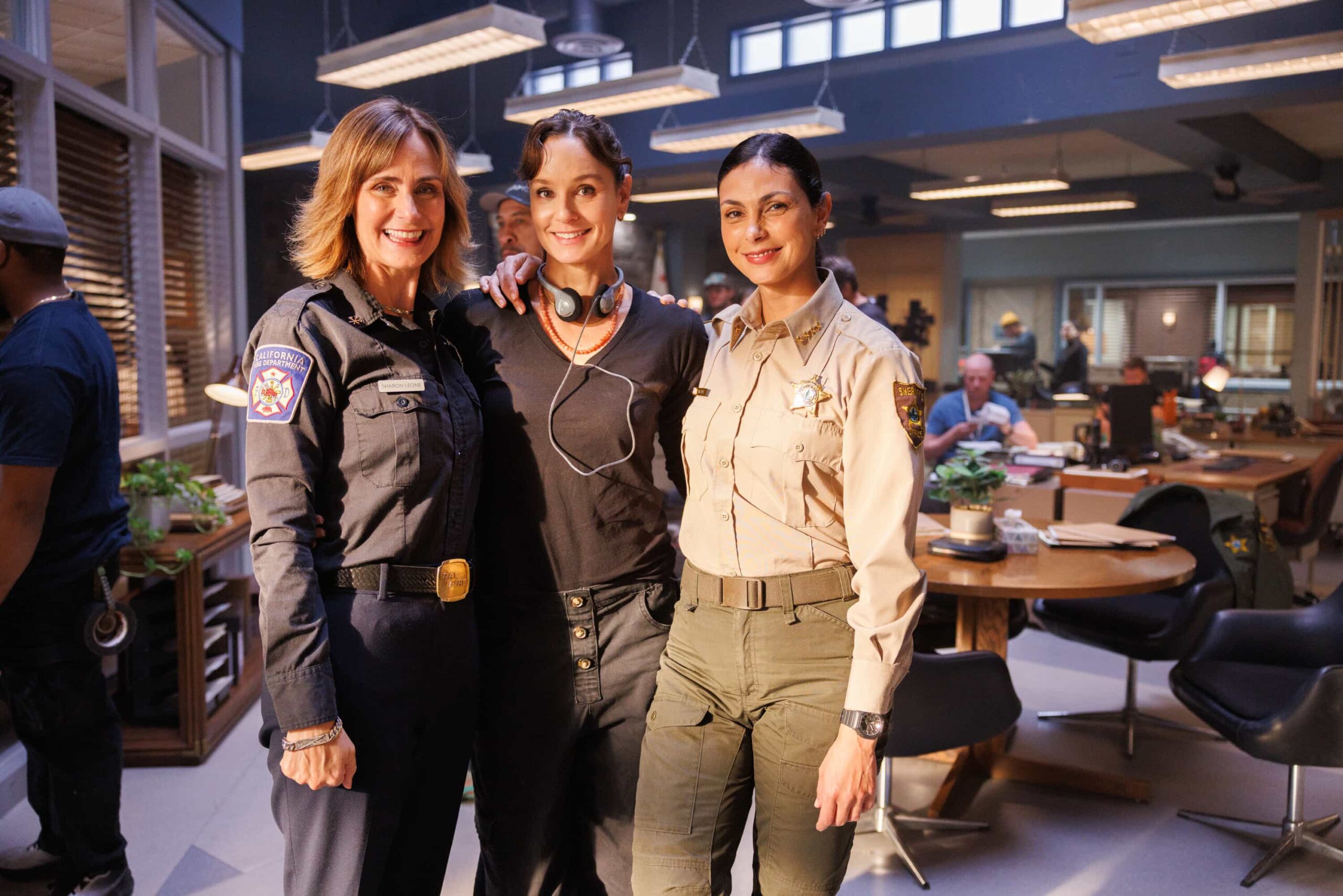 “Death & Taxes” BTS – As cannabis growers in Edgewater scramble to pay their taxes in cash, a violent robbery leaves a man in critical condition and exposes the vulnerability of the legal cannabis trade. Meanwhile, Mickey navigates a tense meal with her stepsister, Sharon (FIRE COUNTRY), on SHERIFF COUNTRY, Friday, Dec. 12 (8:00-9:00 PM, ET/PT) on the CBS Television Network, and streaming on Paramount+ (live and on-demand for Paramount+ Premium plan subscribers, or on-demand for Paramount+ Essential subscribers the day after the episode airs)*. Pictured: Diane Farr, Director Sarah Wayne Callies and Morena Baccarin. Photo: Darren Goldstein/CBS ©2025 CBS Broadcasting, Inc. All Rights Reserved.