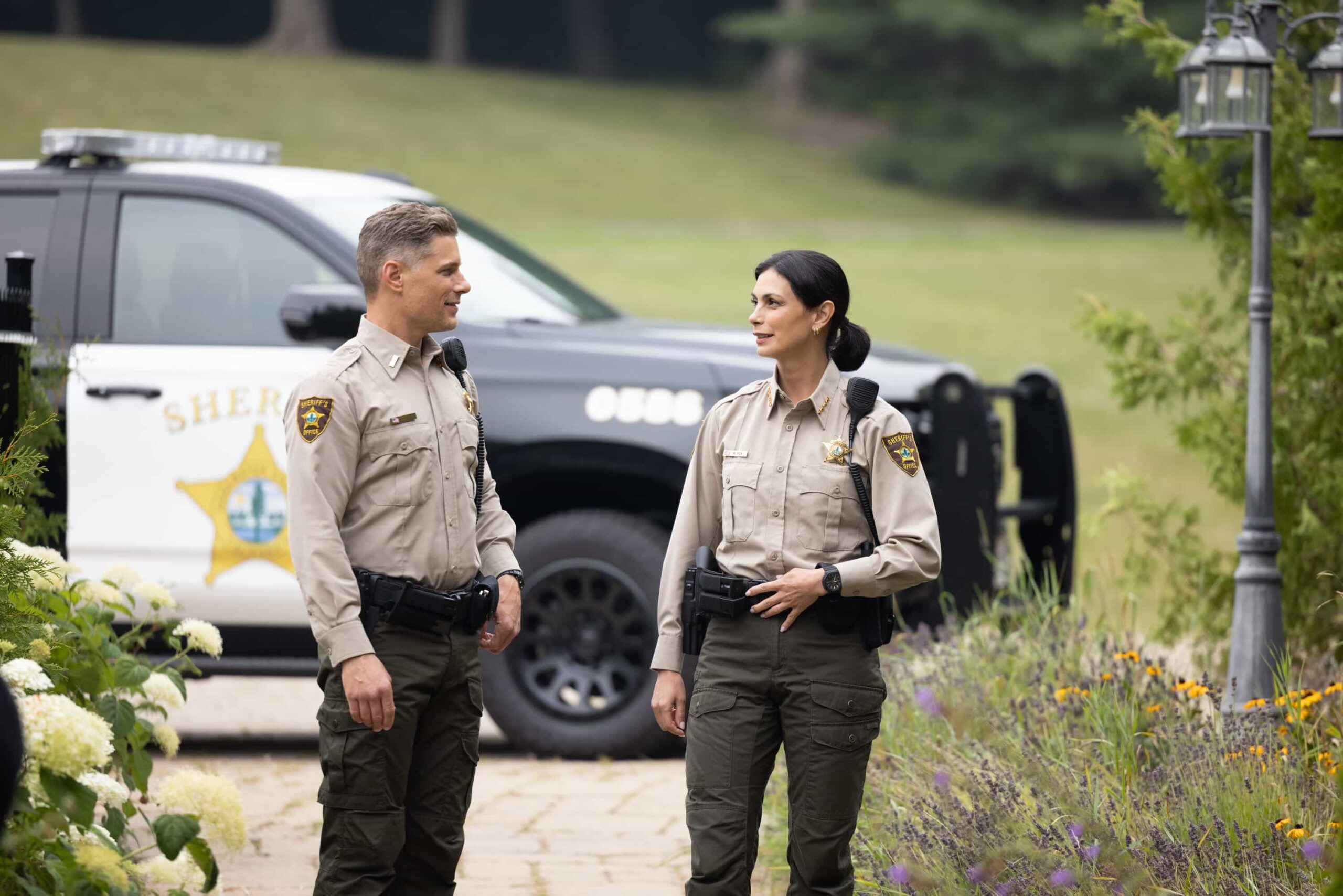 Sheriff Country Season 1 Episode 6 "Exit Interview" – When a body is discovered along the Eel River, Sheriff Mickey Fox and her team launch a homicide investigation that rattles the heart of Edgewater. Meanwhile, Wes risks everything to uncover the truth about the murder, on SHERIFF COUNTRY, Friday, Nov. 21 (8:00-9:00 PM, ET/PT) on the CBS Television Network, and streaming on Paramount+ (live and on-demand for Paramount+ Premium plan subscribers, or on-demand for Paramount+ Essential subscribers the day after the episode airs)*.  Pictured: Matt Lauria and Morena Baccarin. Photo: Darren Goldstein/CBS ©2025 CBS Broadcasting, Inc. All Rights Reserved.