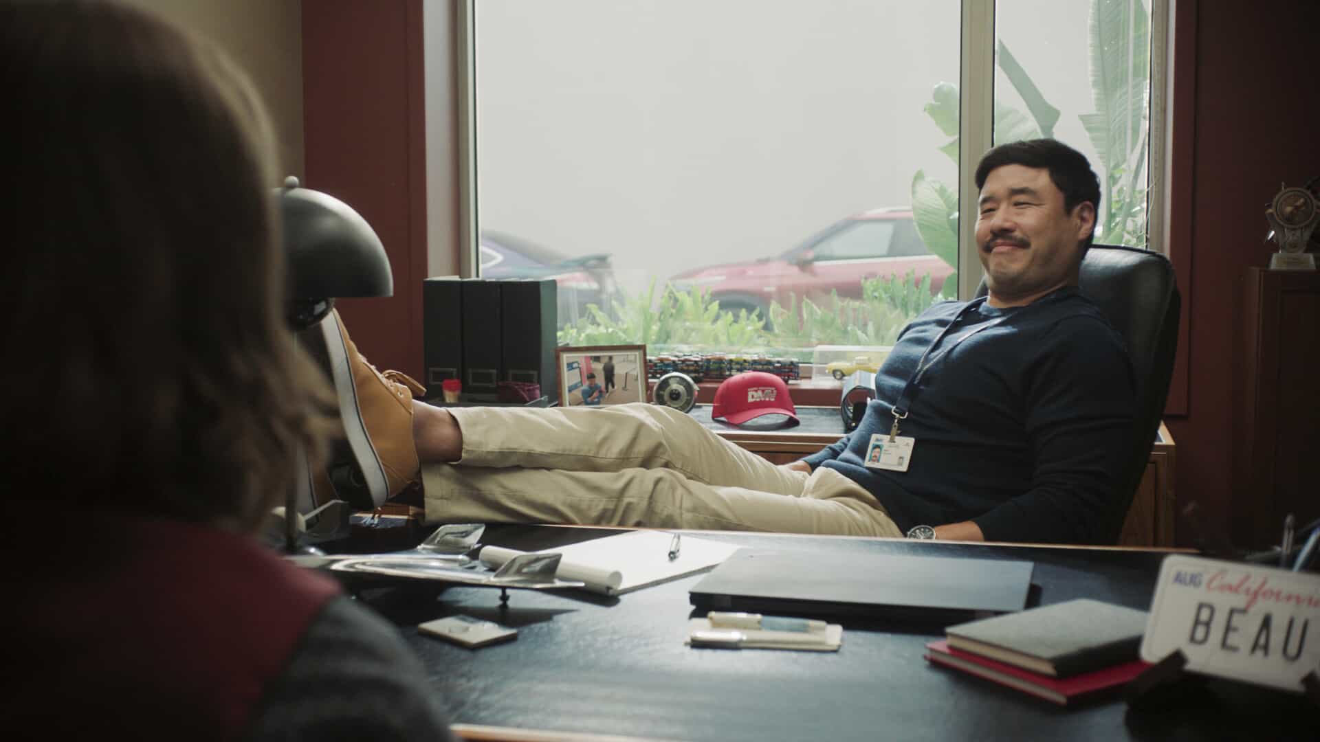 DMV Season 1 Episode 7  “There Is No I in DMV” – Barb takes the team on a field trip to the rival North Hollywood branch to learn the secrets of their success. She begins to doubt herself after meeting their charismatic manager, Beau (Randall Park). Meanwhile, Gregg and Vic get in Colette’s head that Noa prefers risk-takers, on DMV, Monday, Nov. 24 (9:30-10:00 PM, ET/PT) on the CBS Television Network, and streaming on Paramount+ (live and on-demand for Paramount+ Premium plan subscribers, or on-demand for Paramount+ Essential subscribers the day after the episode airs)*. Pictured: Randall Park as Beau Young. Photo: CBS ©2025 CBS Broadcasting, Inc. All Rights Reserved. Highest quality screengrab available.