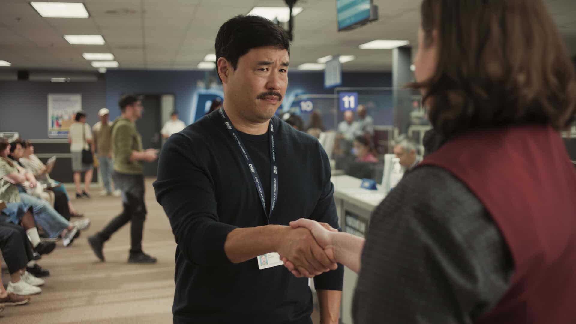 DMV Season 1 Episode 7  “There Is No I in DMV” – Barb takes the team on a field trip to the rival North Hollywood branch to learn the secrets of their success. She begins to doubt herself after meeting their charismatic manager, Beau (Randall Park). Meanwhile, Gregg and Vic get in Colette’s head that Noa prefers risk-takers, on DMV, Monday, Nov. 24 (9:30-10:00 PM, ET/PT) on the CBS Television Network, and streaming on Paramount+ (live and on-demand for Paramount+ Premium plan subscribers, or on-demand for Paramount+ Essential subscribers the day after the episode airs)*. Pictured: Randall Park as Beau Young. Photo: CBS ©2025 CBS Broadcasting, Inc. All Rights Reserved. Highest quality screengrab available.