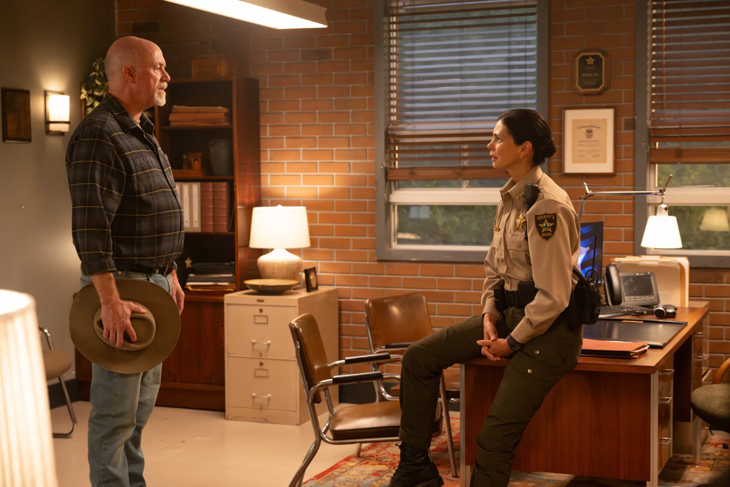 Sheriff Country Season 1 Episode 9 “Crucible, Part 1” – After a father and son flee a secluded ranch run by one of Edgewater’s most power families, Mickey investigates disturbing allegations of abuse and uncovers dangerous secrets, which leads to a tense standoff and confrontation, on SHERIFF COUNTRY, Friday, Dec. 19 (8:00-9:00 PM, ET/PT). Pictured: Michael Gaston as Enoch Barlow and Morena Baccarin as Sheriff Mickey Fox. Photo: Christos Kalohoridis/CBS ©2025 CBS Broadcasting, Inc. All Rights Reserved.