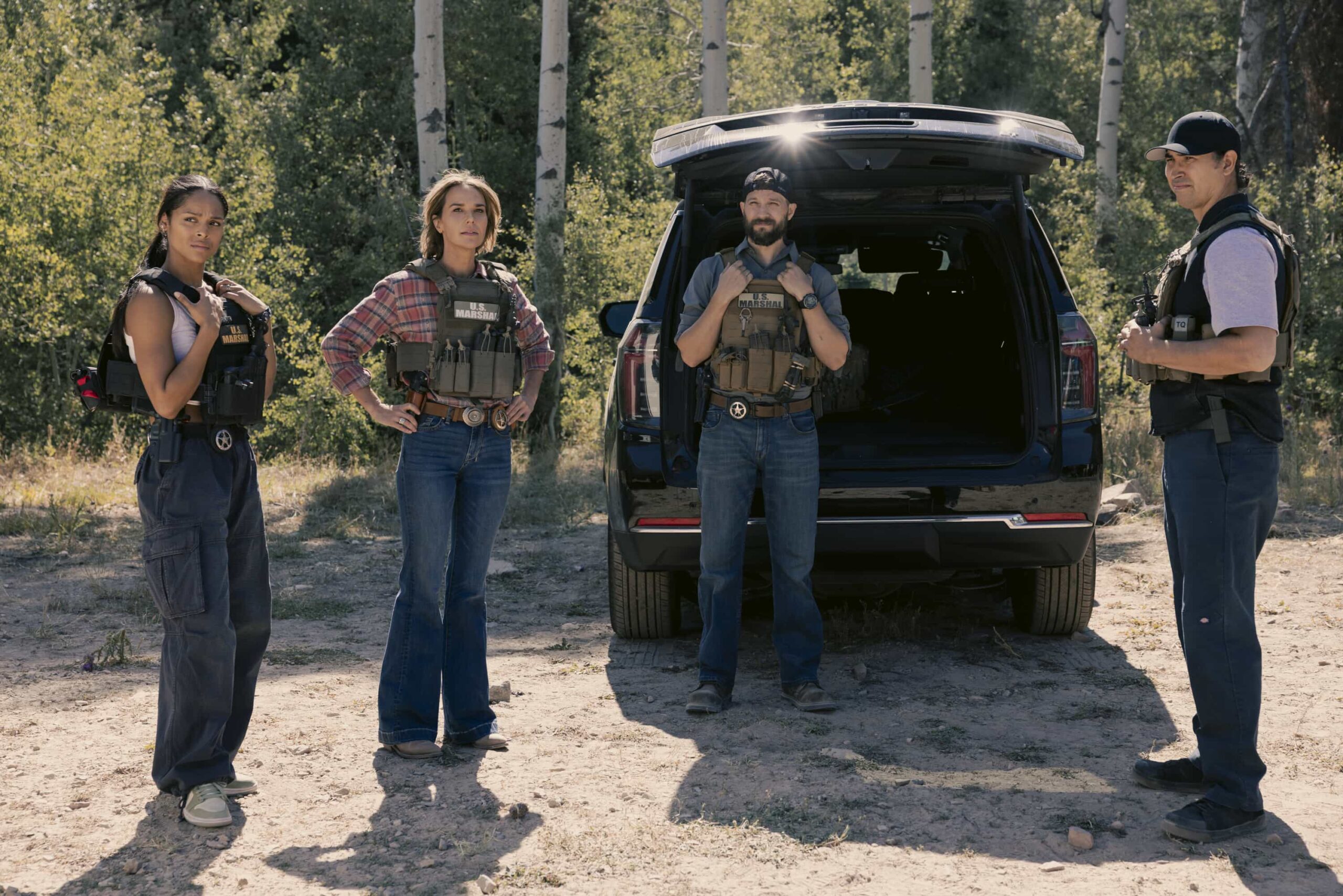 Marshals Season 1 Episode 1 "Piya Wiconi" -- Kayce Dutton reunites with an old SEAL teammate and aids his Marshal unit in hunting down a bomber targeting Broken Rock Reservation. The trail leads to a dangerous encounter with an armed anti-government militia on the series premiere of MARSHALS, Sunday, March 1 (8:00-9:00 PM, ET/PT).  Pictured (L-R): Ash Santos as Andrea, Arielle Kebbel as Belle, Logan Marshall-Green as Pete Calvin, and Tatanka Means as Miles. Photo: Sonja Flemming/CBS ©2025 CBS Broadcasting, Inc. All Rights Reserved.