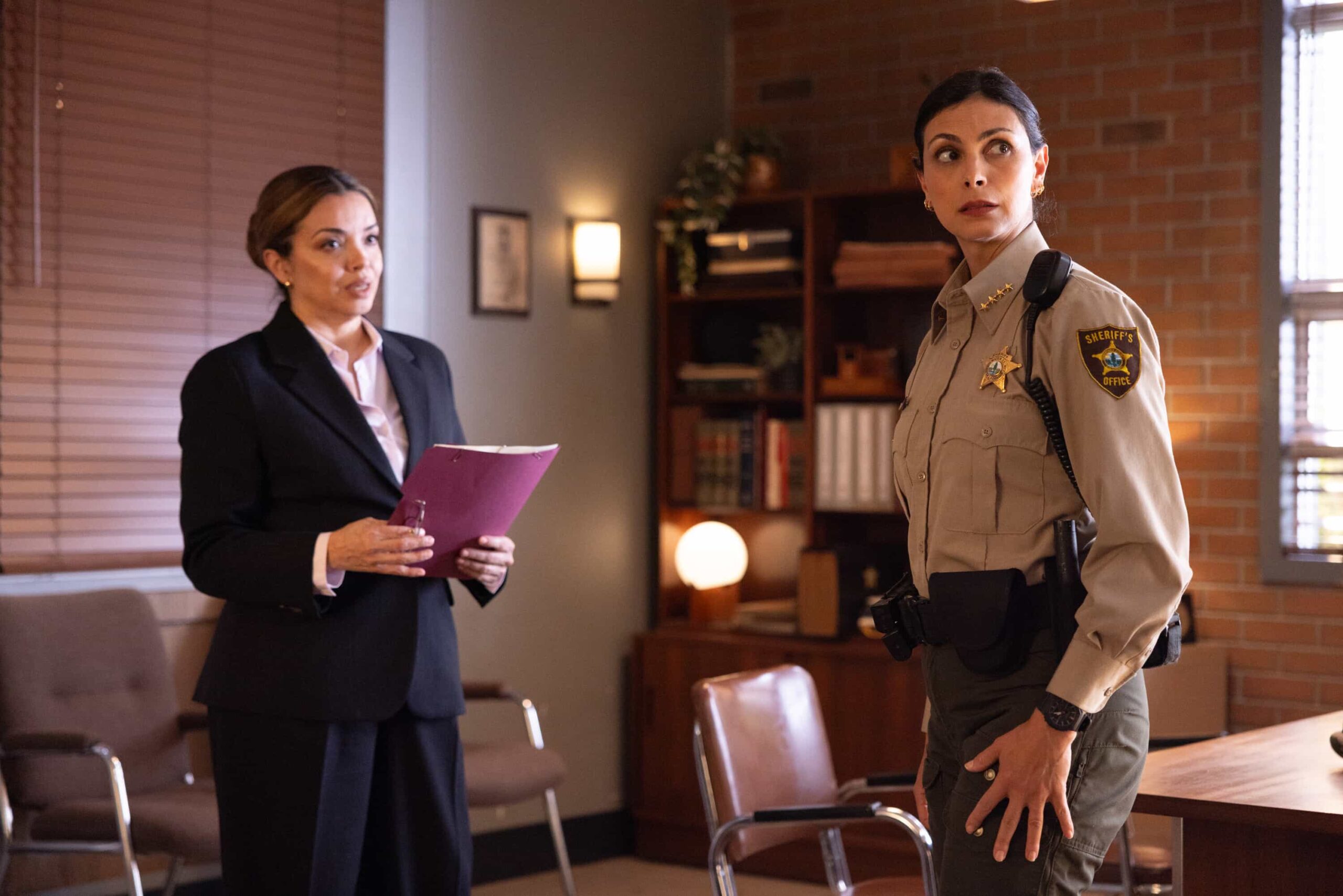 Sheriff Country Season 1 Episode 11 Still “The Aftermath” – When a courthouse security test ends in a shocking murder, Sheriff Mickey Fox uncovers a dangerous conspiracy reaching deep into Edgewater’s justice system.Pictured: Anel Lopez-Gorham as Judge Thompson and Morena Baccarin as Sheriff Mickey Fox. Photo: Darren Goldstein/CBS ©2025 CBS Broadcasting, Inc. All Rights Reserved.