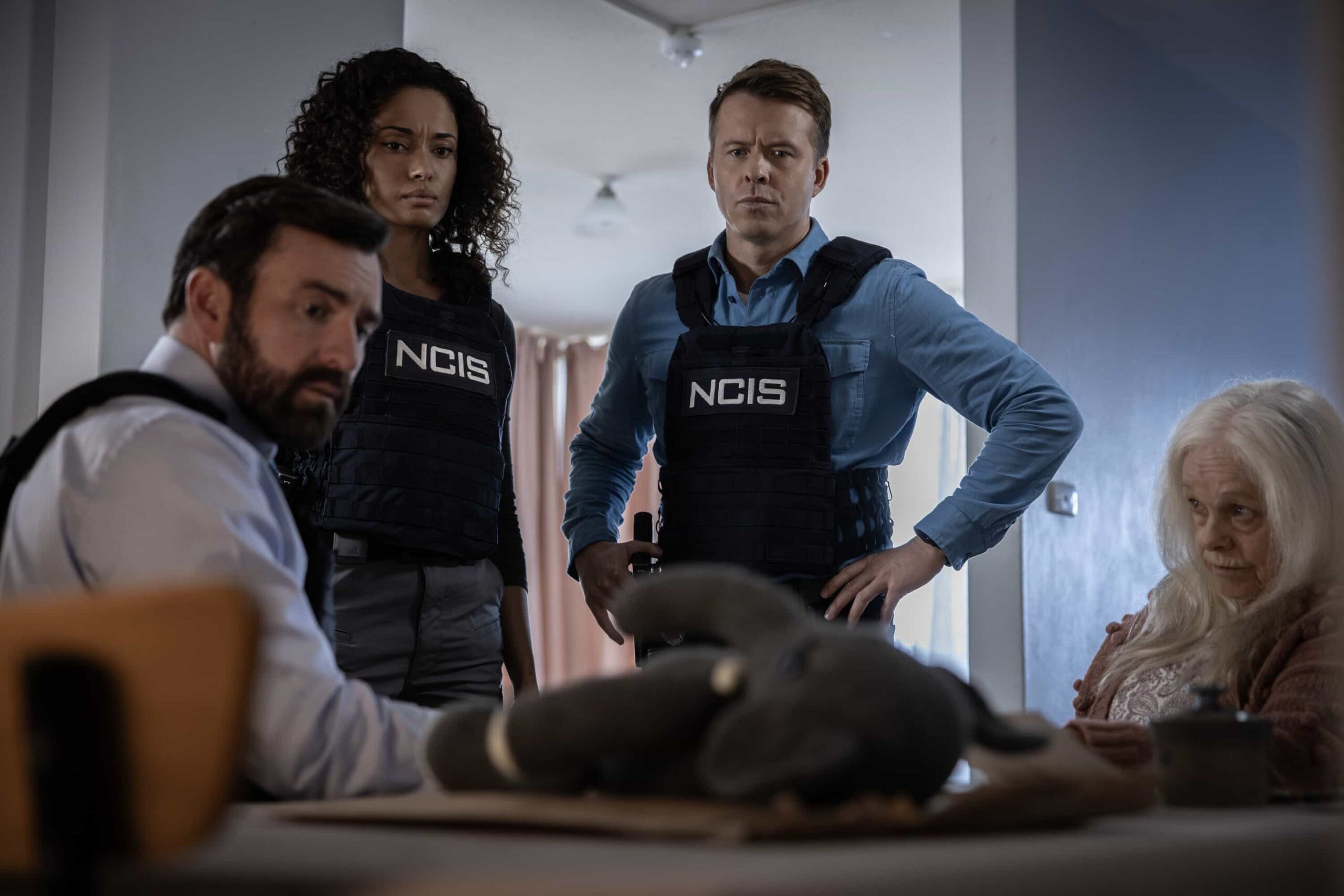 NCIS Sydney Season 3 Episode 12 - L-R: Johnny Carr as Rory Latham, Olivia Swann as NCIS Special Agent Captain Michelle Mackey, Todd Lasance as AFP Liaison Officer Sergeant Jim \'JD\' Dempsey, and Lynette Curran as Alana Coombs  in NCIS: Sydney episode 12, season 3 streaming on Paramount+, 2026. Photo Credit:  Daniel Asher Smith/Paramount+