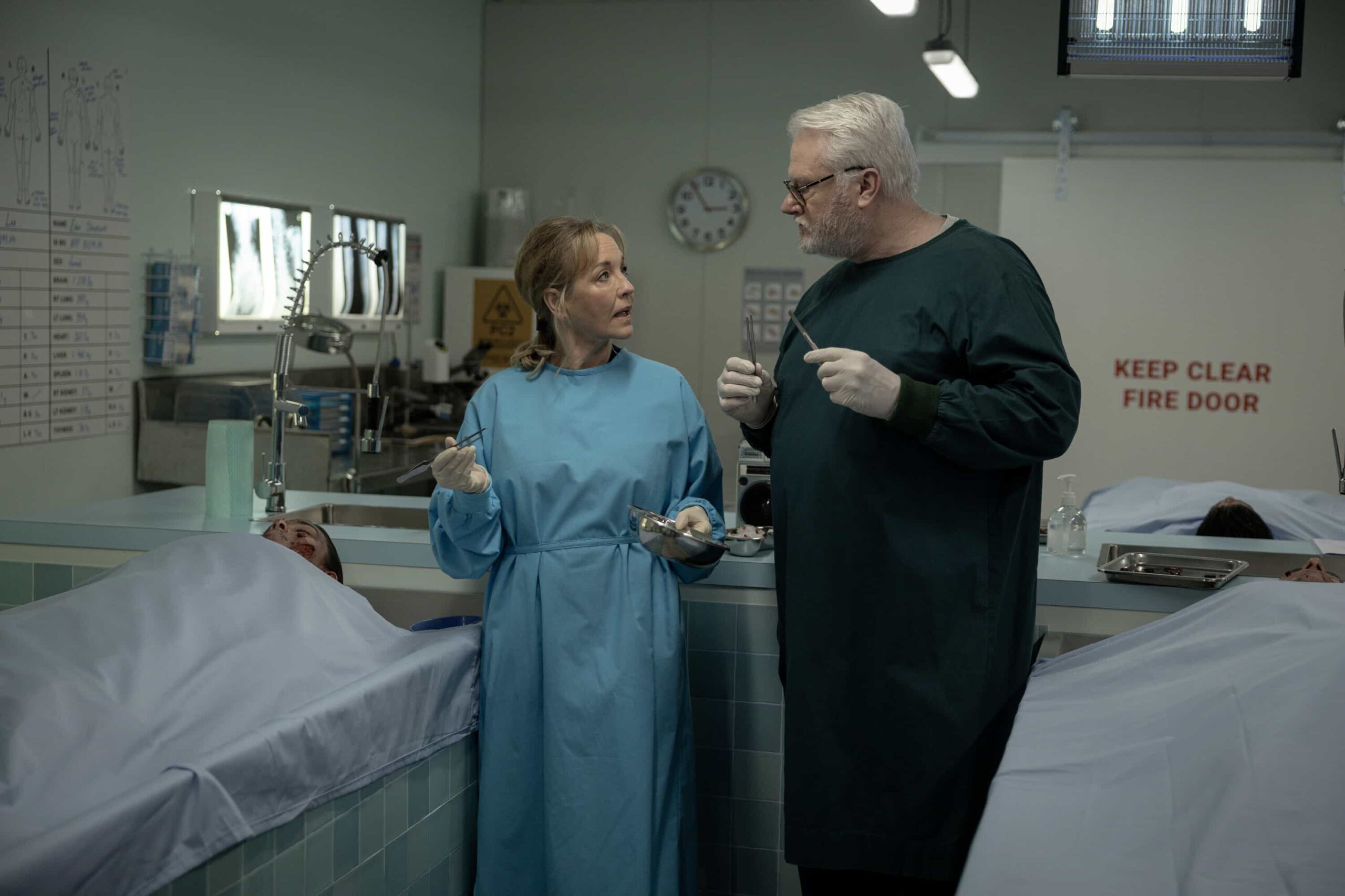 NCIS Sydney Season 3 Episode 12 Still - Lone Wolf: Part One - Rebecca Gibney as Nia Williams and William McInnes as Forensic Pathologist Dr. Roy Penrose in NCIS: Sydney episode 12, season 3 streaming on Paramount+, 2026. Photo Credit:  Daniel Asher Smith/Paramount+