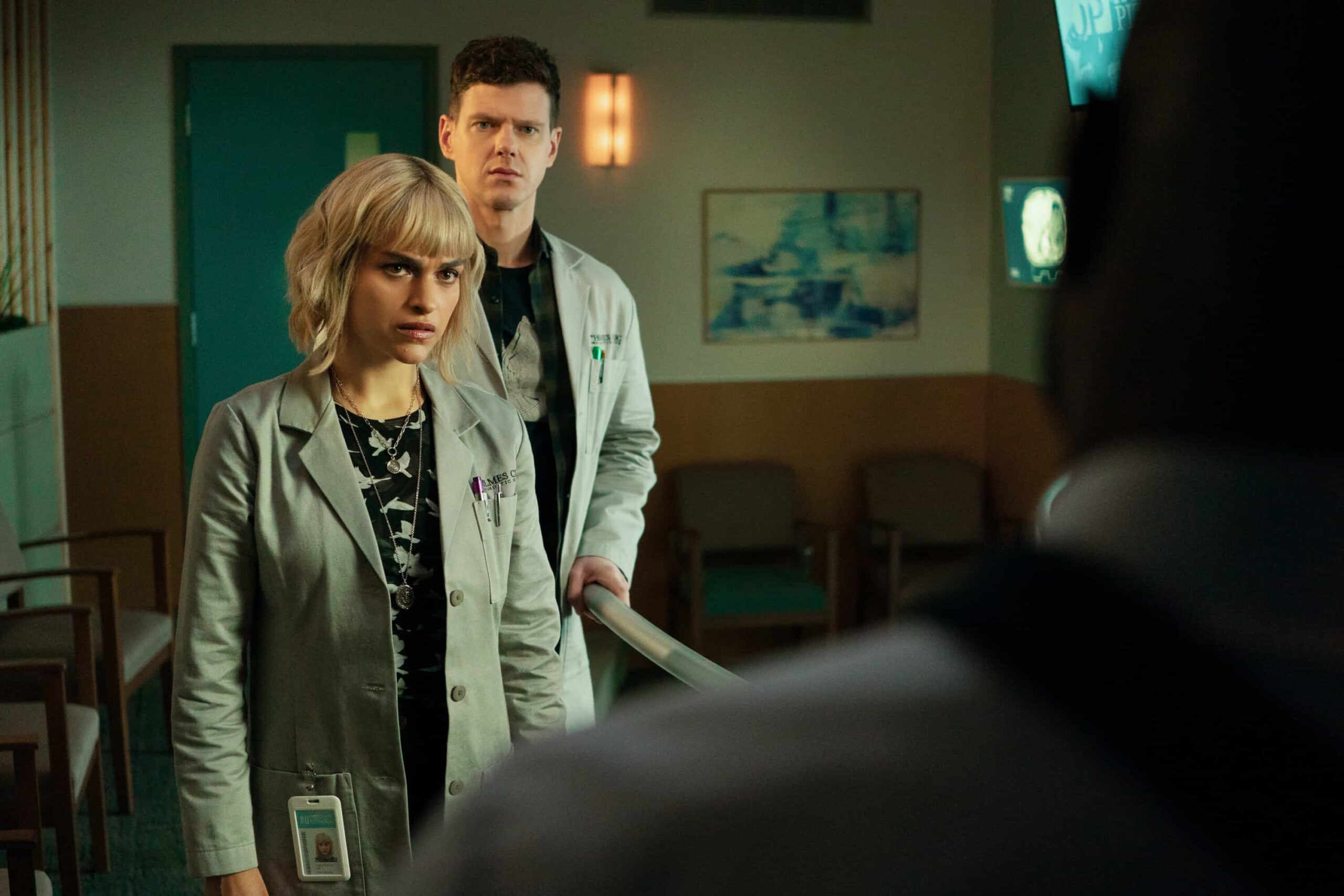 Watson Season 2 Episode 17 Picture - "Unsolved Mysteries" -- Coverage of the CBS Original Series WATSON, scheduled to air on the CBS Television Network.   Pictured (L-R): Eve Harlow as Dr. Ingrid Derian and Peter Mark Kendall as Dr. Adam Croft   Photo: Colin Bentley/CBS ©2026 CBS Broadcasting, Inc. All Rights Reserved.