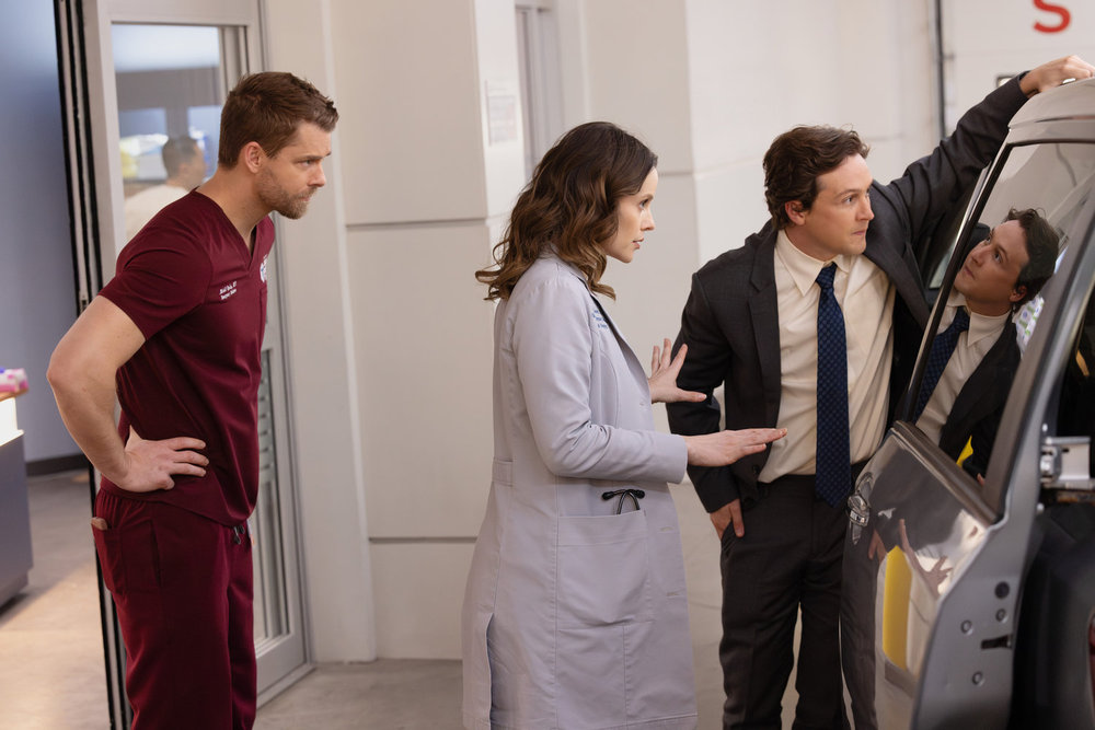 CHICAGO MED Season 11 Episode 19 -- "Exit Strategies" Episode 1119 -- Pictured: (l-r) Luke Mitchell as Dr. Mitch Ripley, Sarah Ramos as Dr. Caitlin Lenox, Logan Miller as Kip -- (Photo by: George Burns Jr/NBC)