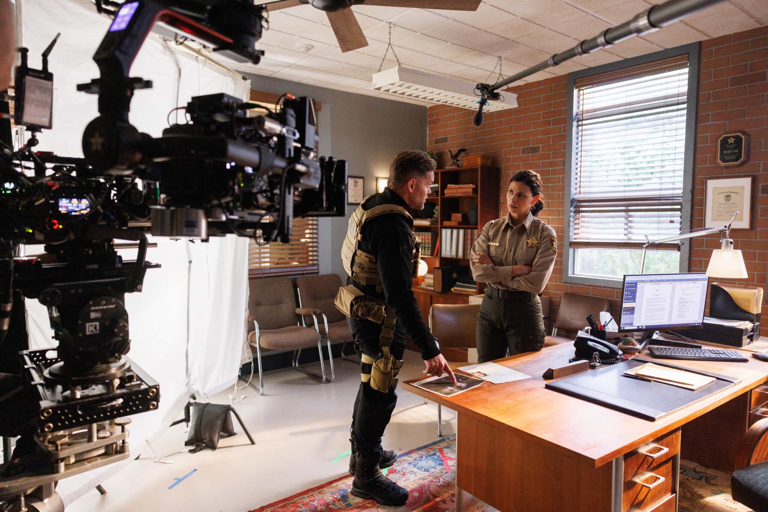BTS “The Gambler” – A dramatic federal crackdown rocks Edgewater and forces Sheriff Mickey Fox to confront a sprawling investigation that pits loyalty to her community against the reach of the DEA. The case pushes Mickey closer to home than ever before with consequences for the people she loves the most, on SHERIFF COUNTRY, Friday, May 8 (8:00-9:00 PM, ET/PT) on the CBS Television Network, and streaming on Paramount+ (live and on-demand for Paramount+ Pictured: Wes Chatham and Morena Baccarin. Photo: Darren Goldstein/CBS ©2026 CBS Broadcasting, Inc. All Rights Reserved.