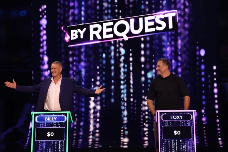 Billy Billingham and Jason Foxy Fox standing at their game show podiums competing against each other.
