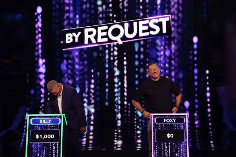 Billy Billingham and Jason Foxy Fox standing at their game show podiums competing against each other.