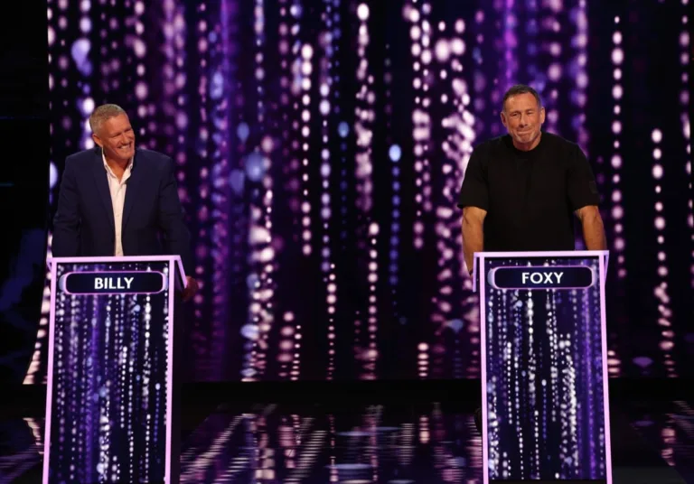 Billy Billingham and Jason Foxy Fox standing at their game show podiums competing against each other.