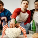 Friends watching football game together eating popcorn and snacks