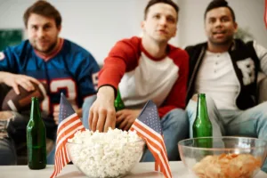 Friends watching football game together eating popcorn and snacks