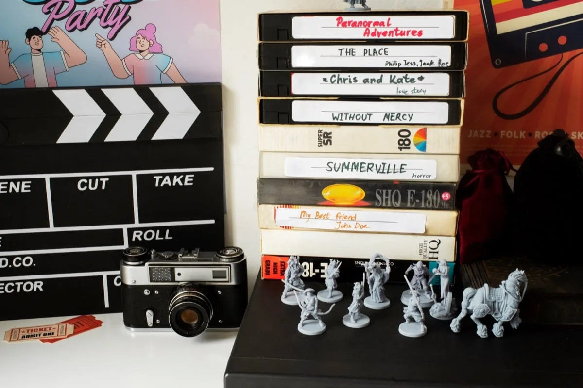 Stack of vintage VHS tapes next to clapperboard and miniatures
